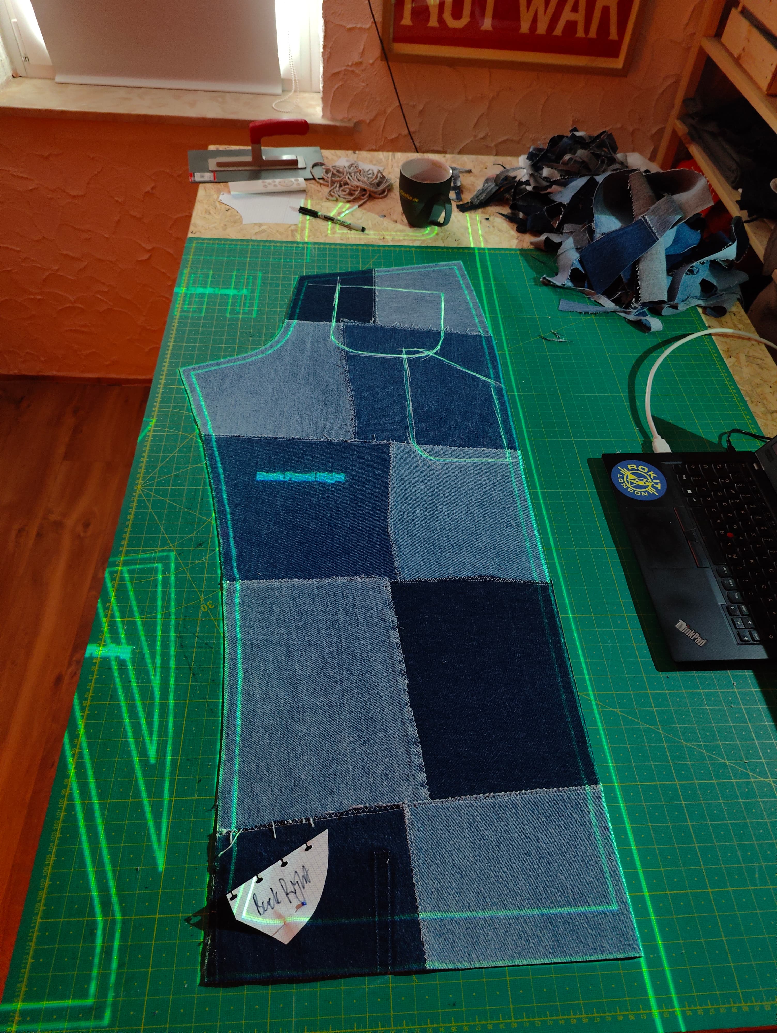 Projected trouser pattern over patchwork denim panel on cutting table